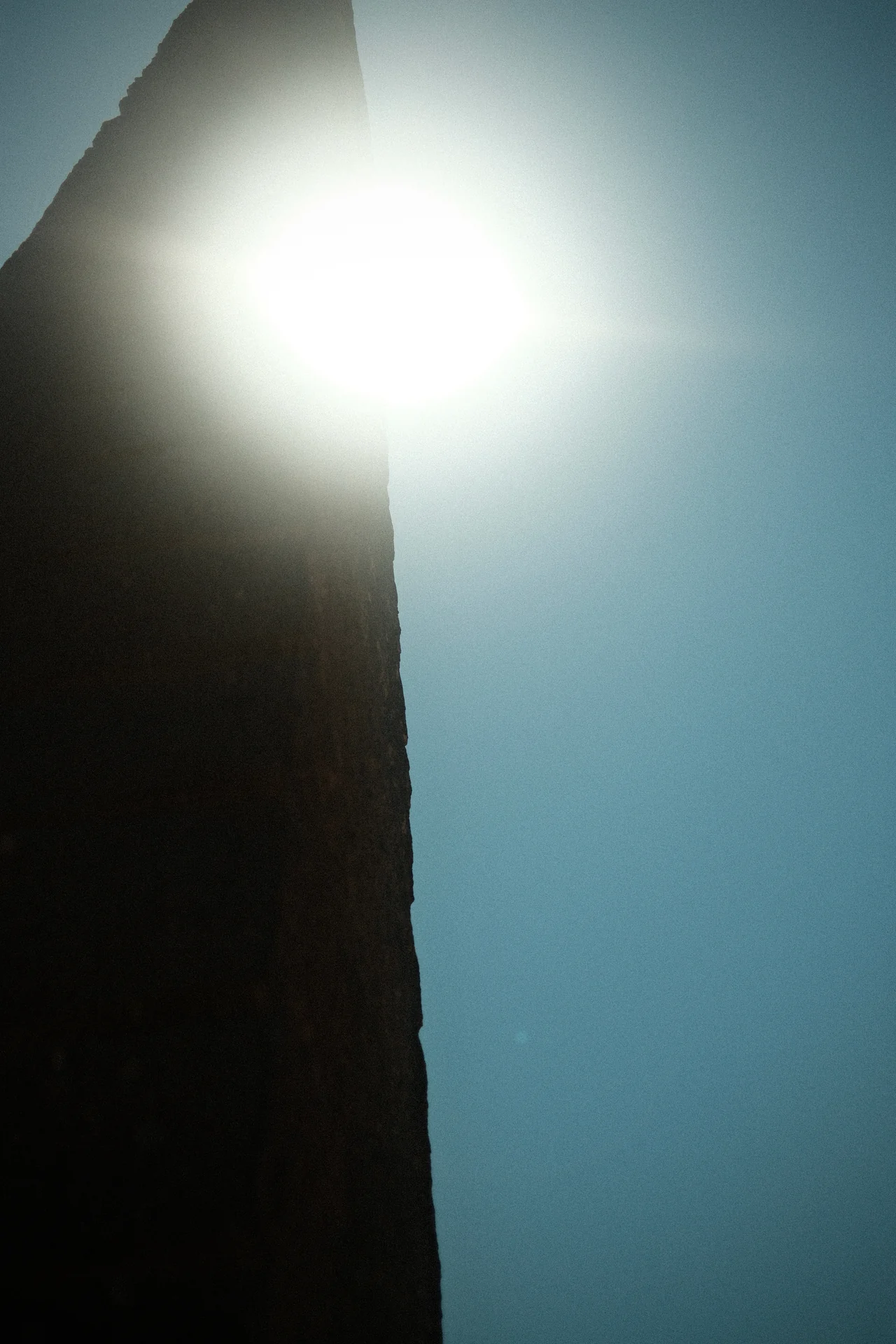 Die Sonne erscheint an der Kante einer dunklen Wand.