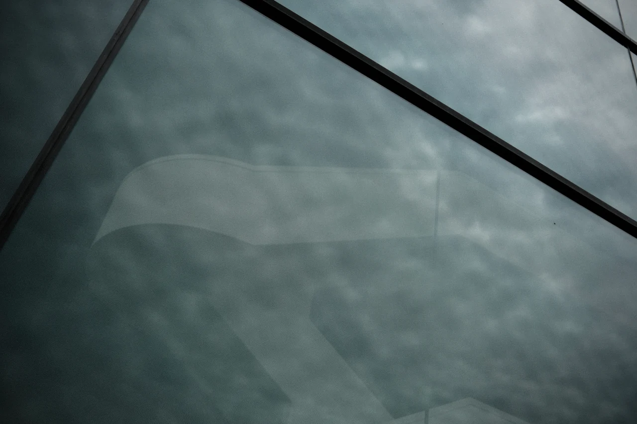 Wolken hinter einer Glasfläche mit diagonalen Streben.