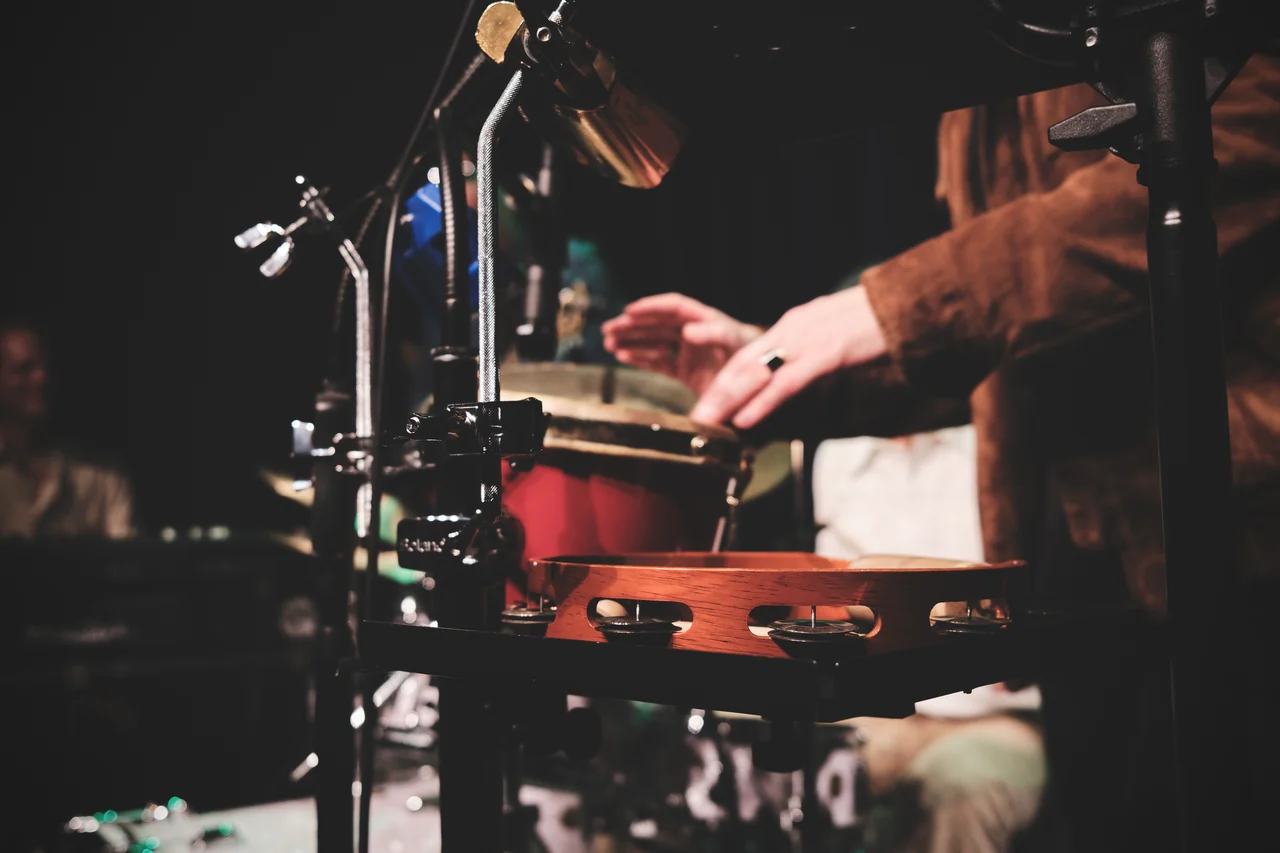 Hände spielen Percussion zwischen Mikrofonen und Instrumenten.