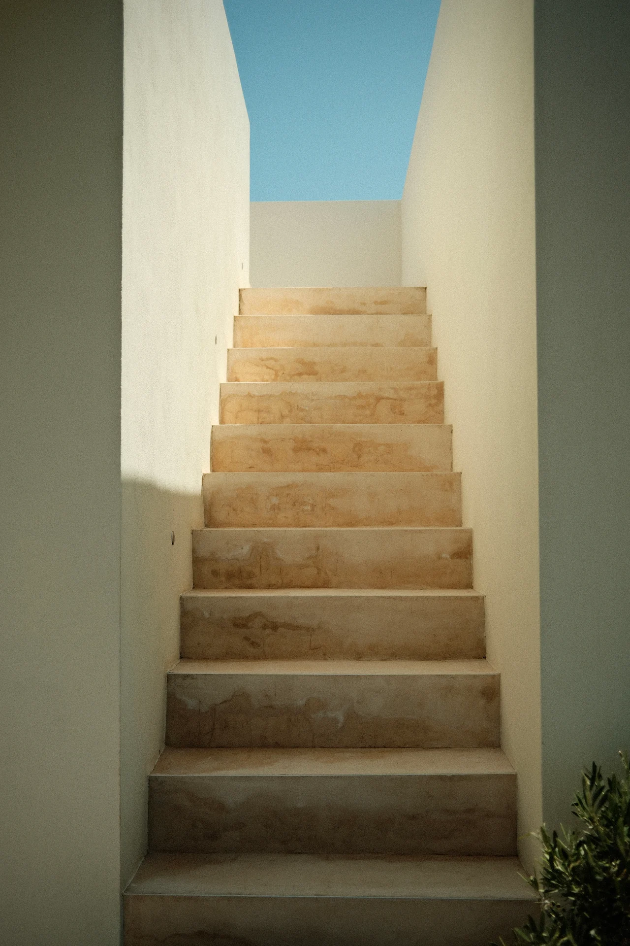 Eine helle Steintreppe zwischen zwei Wänden führt zum Himmel.